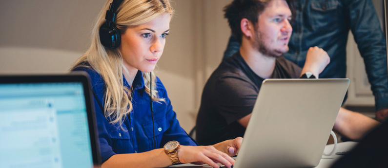 Information Technology professional wearing a headset and working on a laptop.